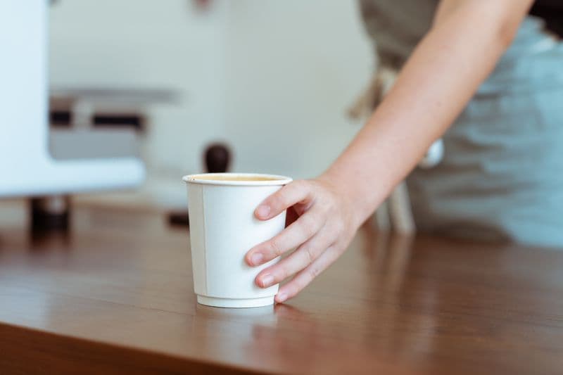 Barista serving cup at espresso machine